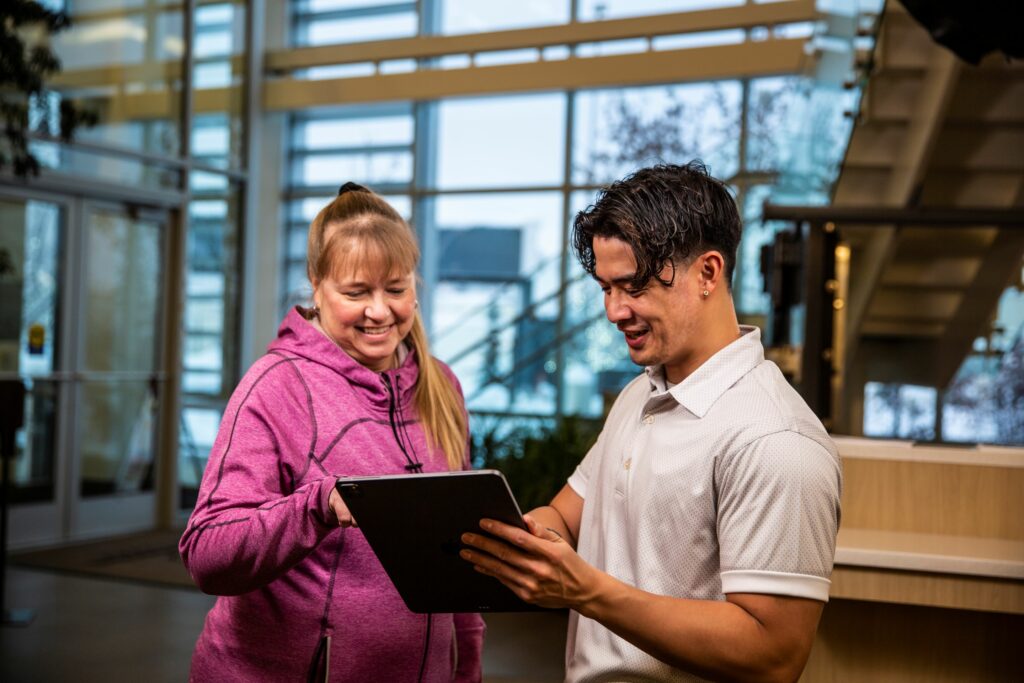 Man and woman smiling while looking at a tablet together, reviewing their banking options.