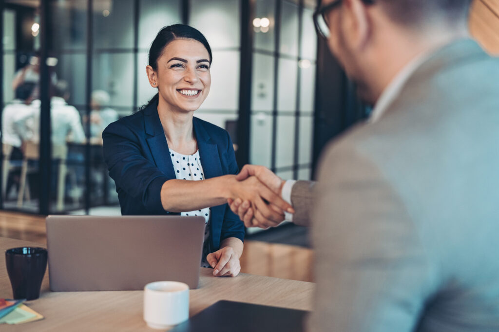 Business persons talking and shaking hands in an office.