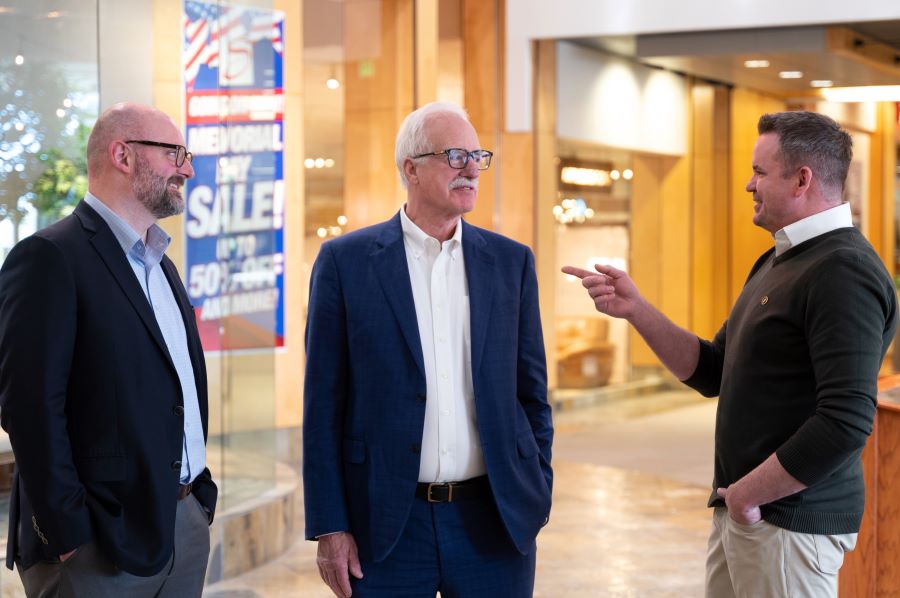 Three men conversing in a stylish lobby.