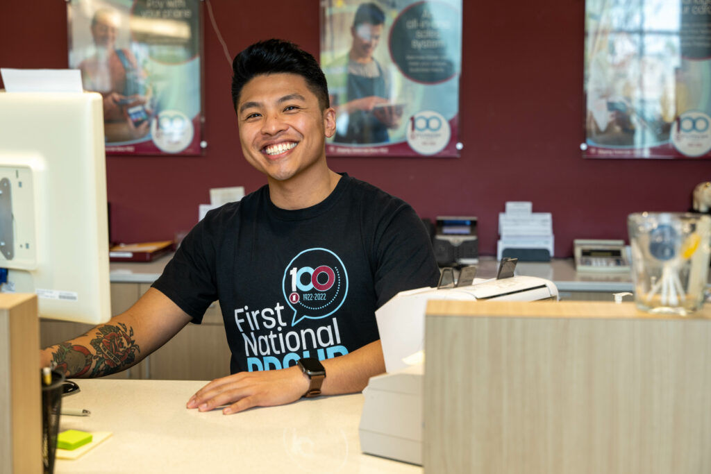 Friendly employee dressed in a black shirt smiles at the front desk, creating an inviting atmosphere for guests arriving.