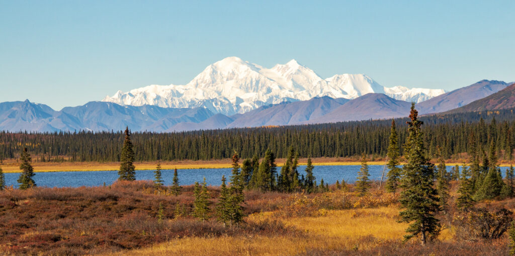 A panoramic image of a mountain range far away, emphasizing the stunning heights and serene atmosphere of the wilderness.