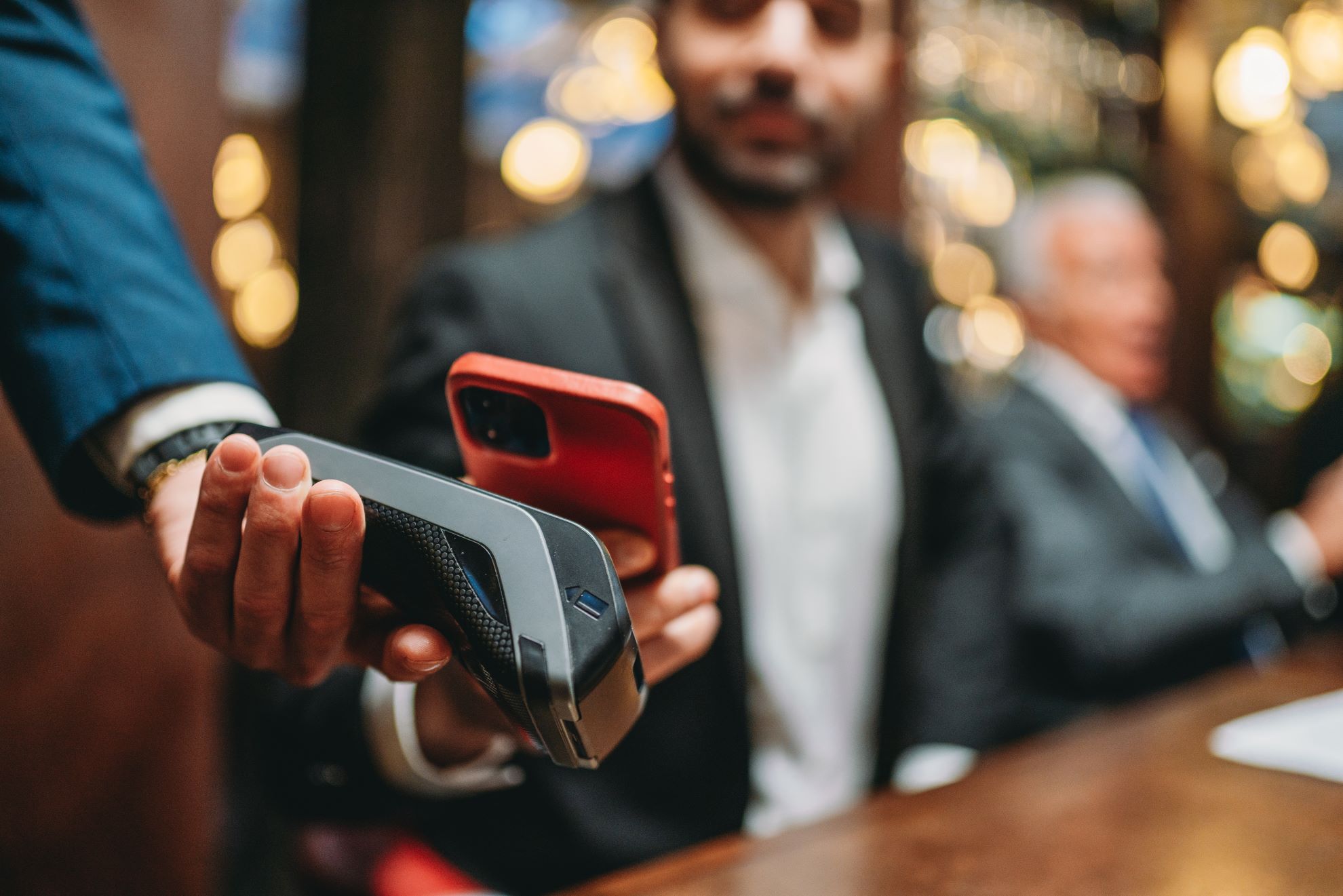 A man wearing a tailored suit holds a cell phone.