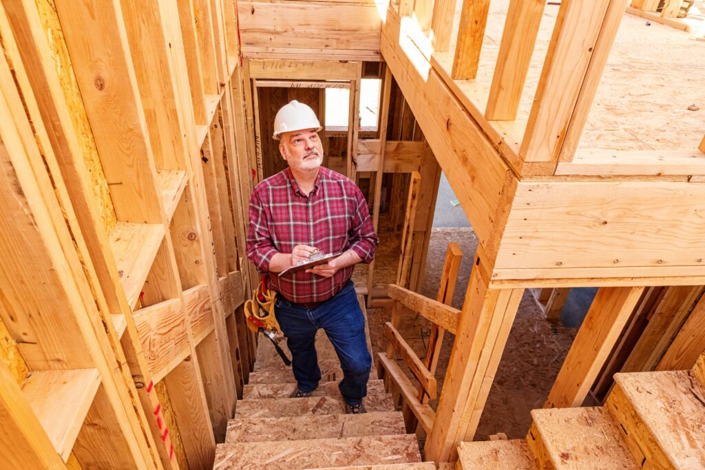 A construction worker stands within a wooden framework, overseeing the building process of a new structure.